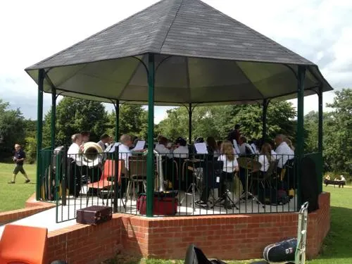 A crowd of visitors gathered under large pyramidal shade structures in an outdoor garden area with raised brick beds and climbing plants.