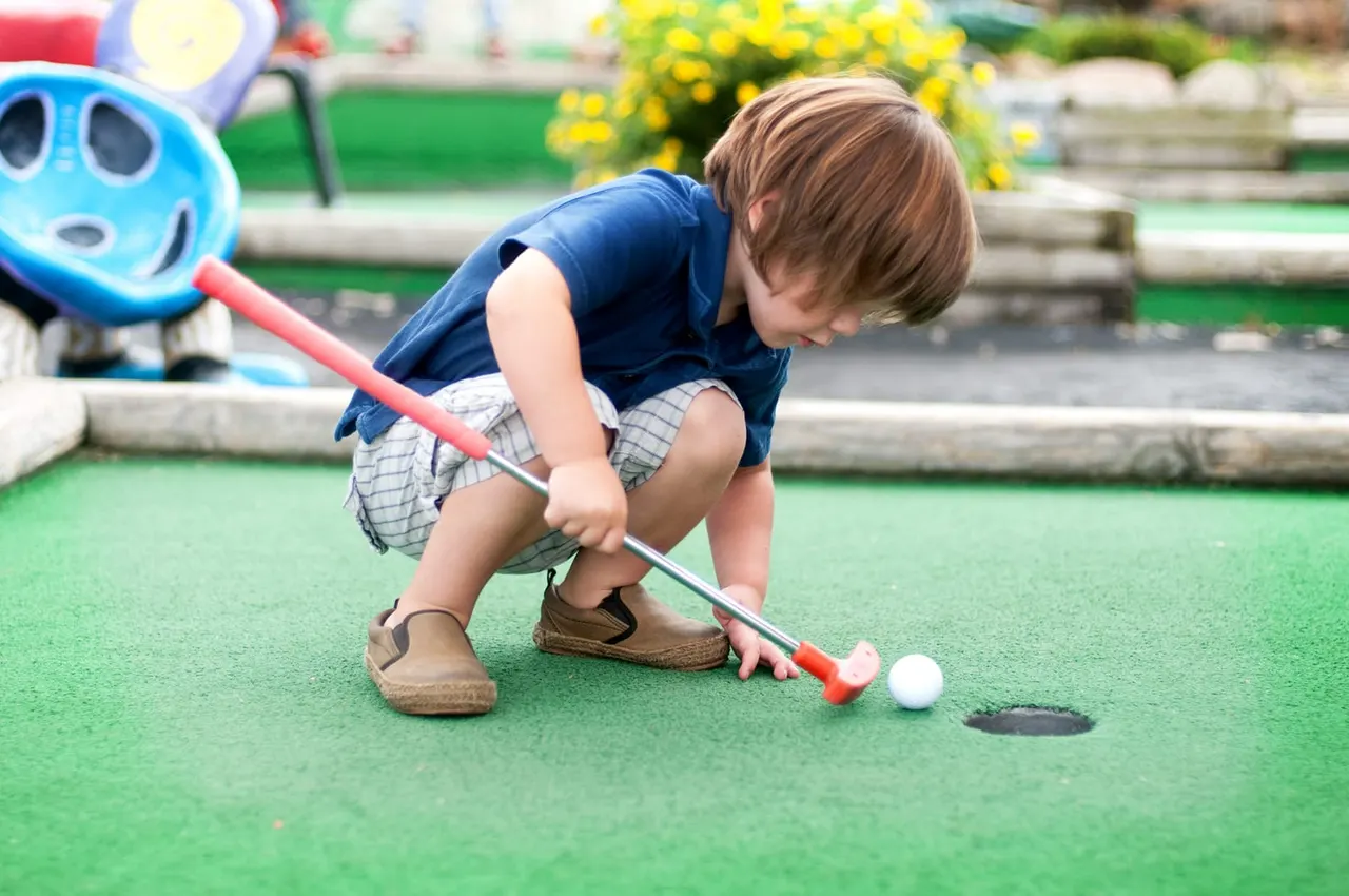 Child putting on outdoor mini golf turf at Ballers and Hackers Hucknall