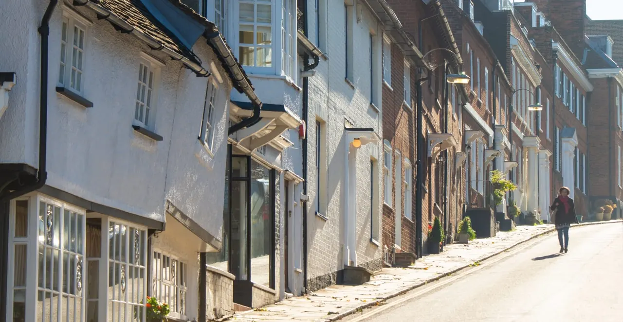 Historic cobbled street lined with traditional brick and whitewashed buildings, with a person walking in the distance.
