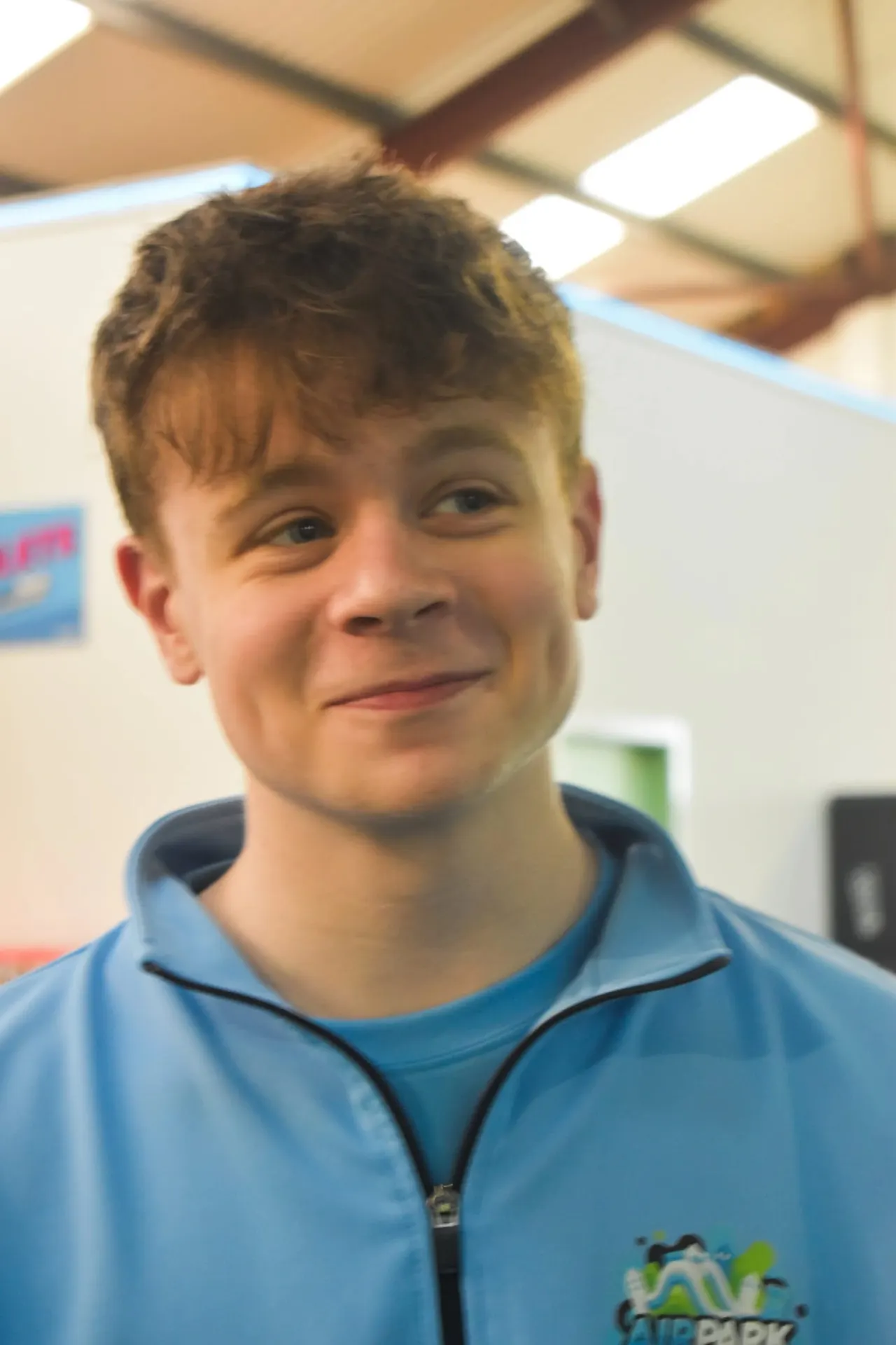Young person wearing a blue activity jacket indoors at a leisure venue.