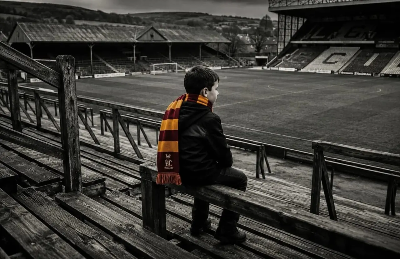 A child wearing a burgundy and gold striped scarf sits on wooden stadium seating overlooking a football pitch.