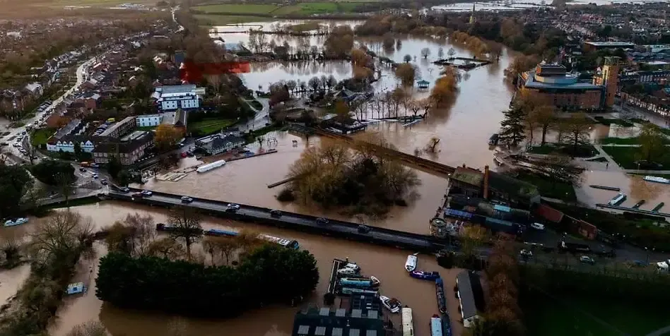 Aerial view of a town with flooded waterways, boats, and surrounding buildings during winter.