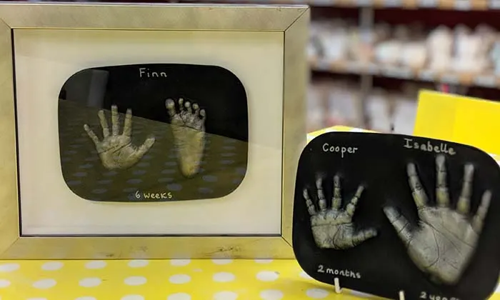 Two framed hand and footprint castings of infants labelled with names and ages.