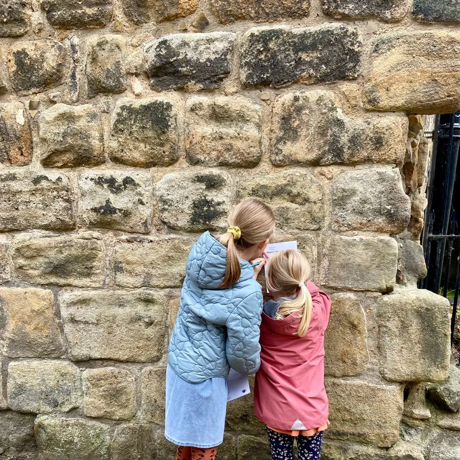 Two young children looking at a stone wall at a historic site.