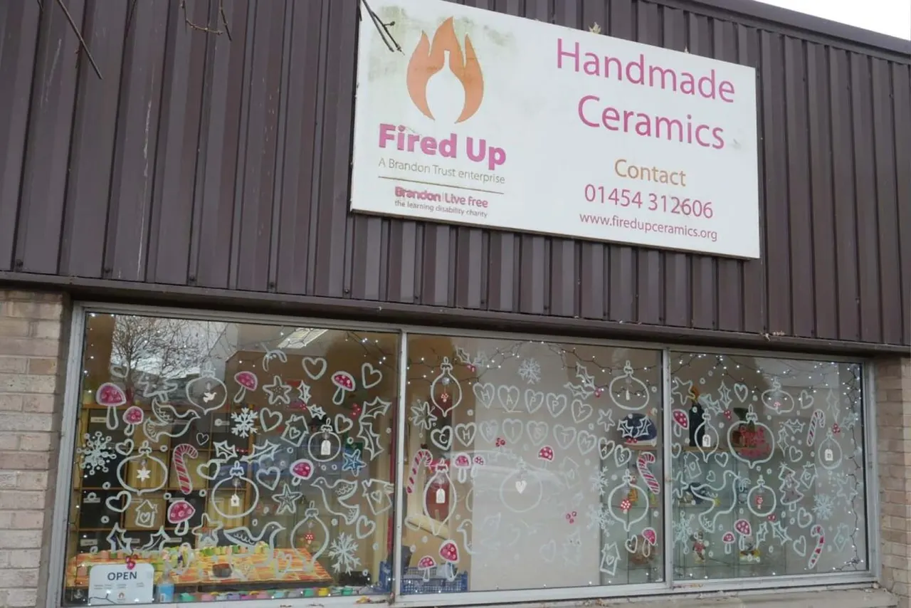 Storefront of Fired Up Ceramics with festive window display featuring hand-drawn Christmas decorations and baubles.