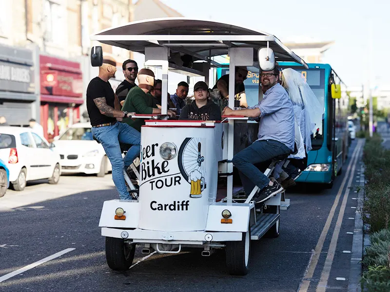 Group of people enjoying a guided beer bike tour through an urban street in Cardiff.