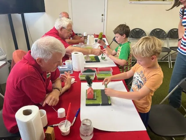 Older adults and children doing a craft activity together at a table indoors.