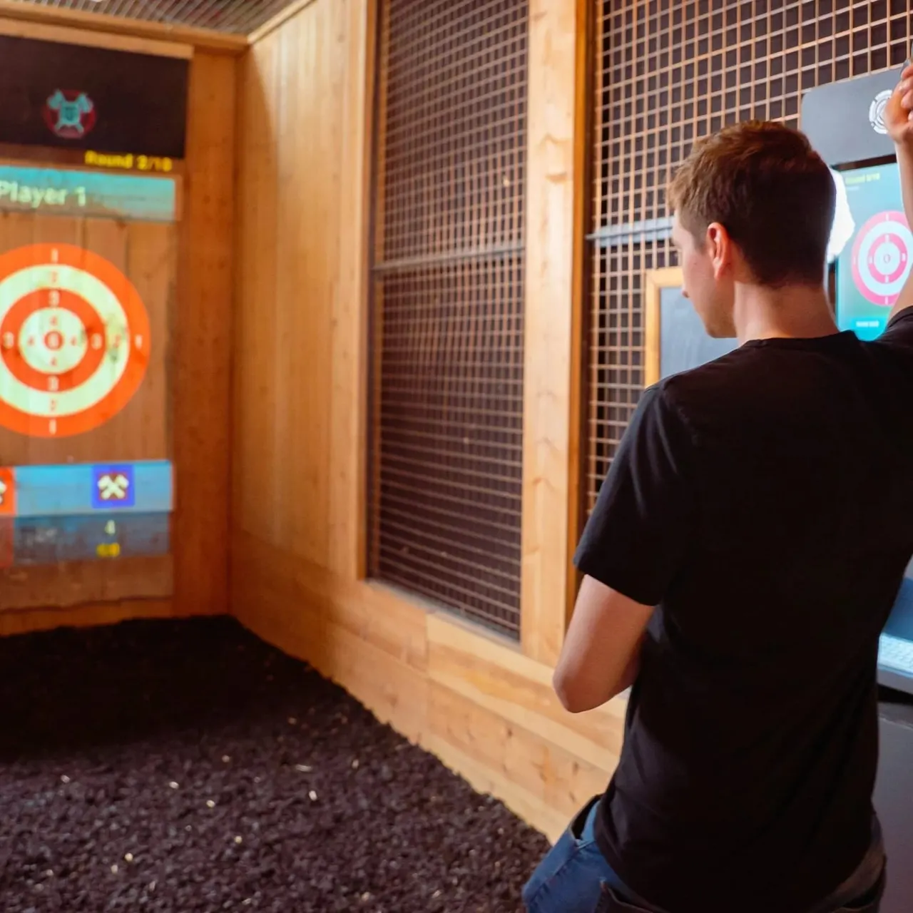 A young person playing an interactive throwing game at a target display screen in an indoor games venue.