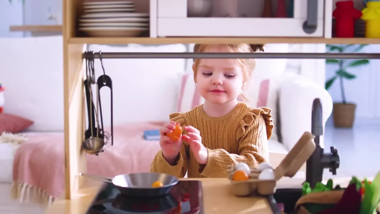 Toddler playing in a toy kitchen, holding a toy fruit above a pan.