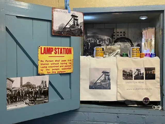 Museum display about mining history featuring vintage photographs, signage, and artefacts related to Snibston Mine.