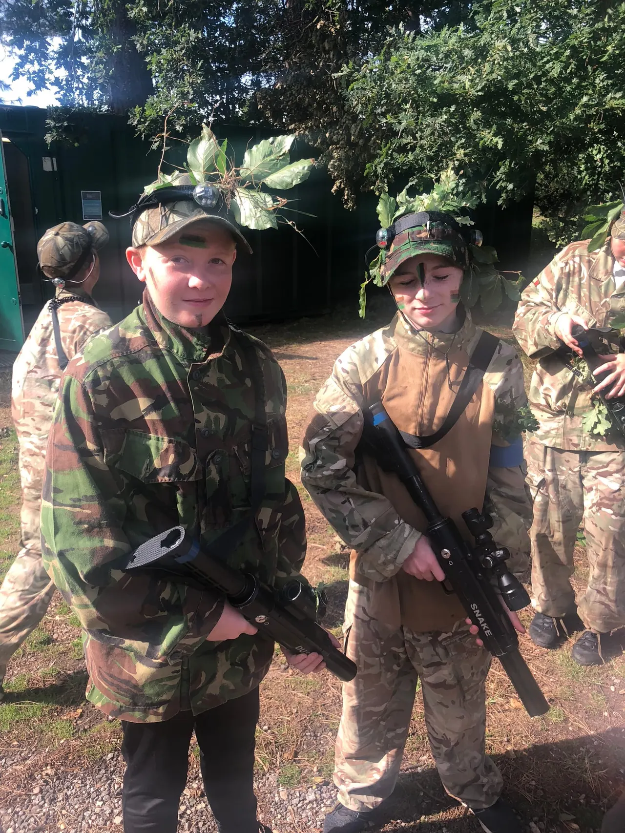 Portrait of a child in camouflage holding a laser tag rifle outdoors