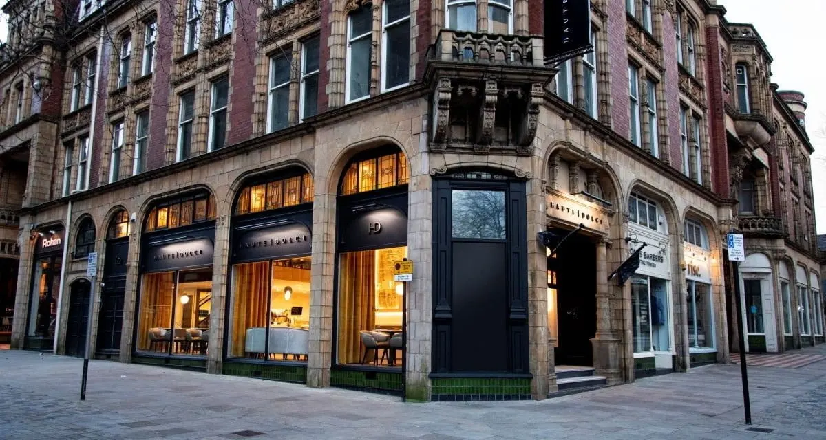 Historic Victorian corner building with illuminated shop fronts at street level and residential windows above.