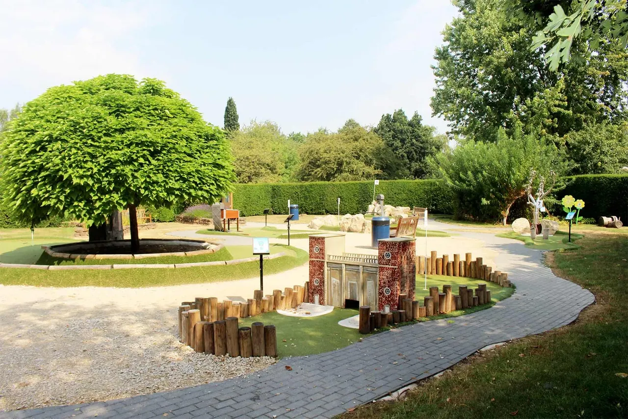 Outdoor adventure golf course with miniature abbey gatehouse obstacle and hedges at Rufford