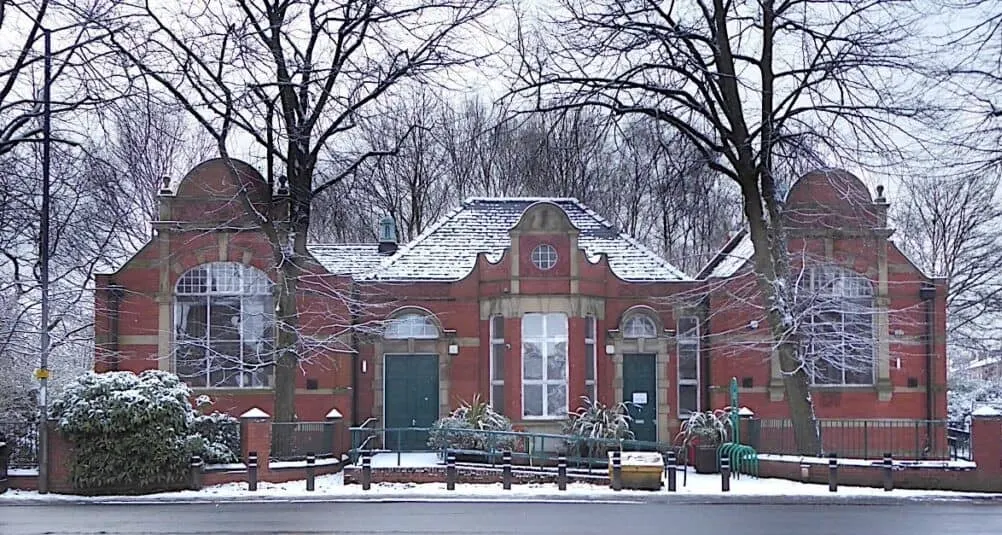 Victorian red brick building with distinctive turrets in winter, surrounded by bare trees and snow.