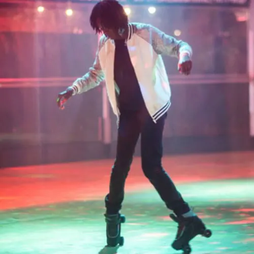 Person skating on illuminated roller disco floor beneath coloured stage lighting.