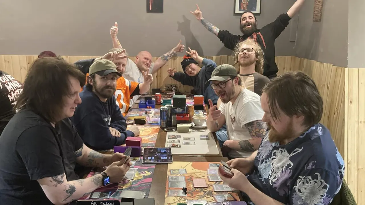 Large group of people enjoying board games and socialising around a table indoors.