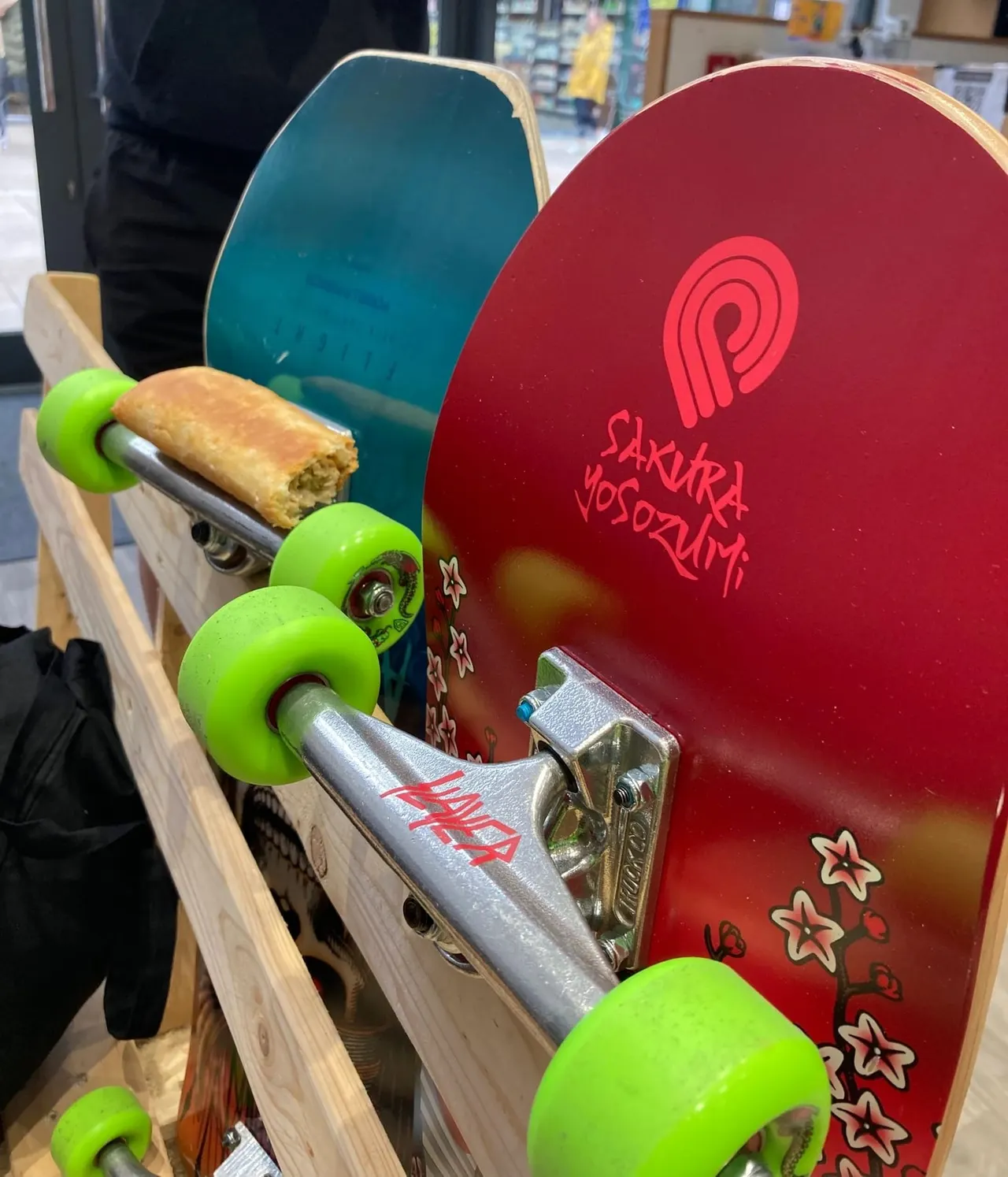 Skateboard decks displayed with bright green wheels and metal trucks in a skate shop.