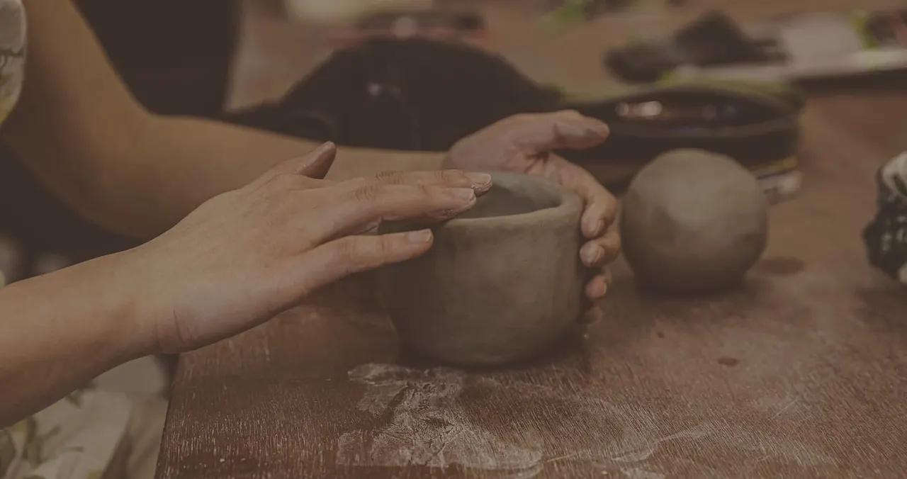 Child's hands shaping wet clay on a pottery wheel during a hands-on ceramics workshop.