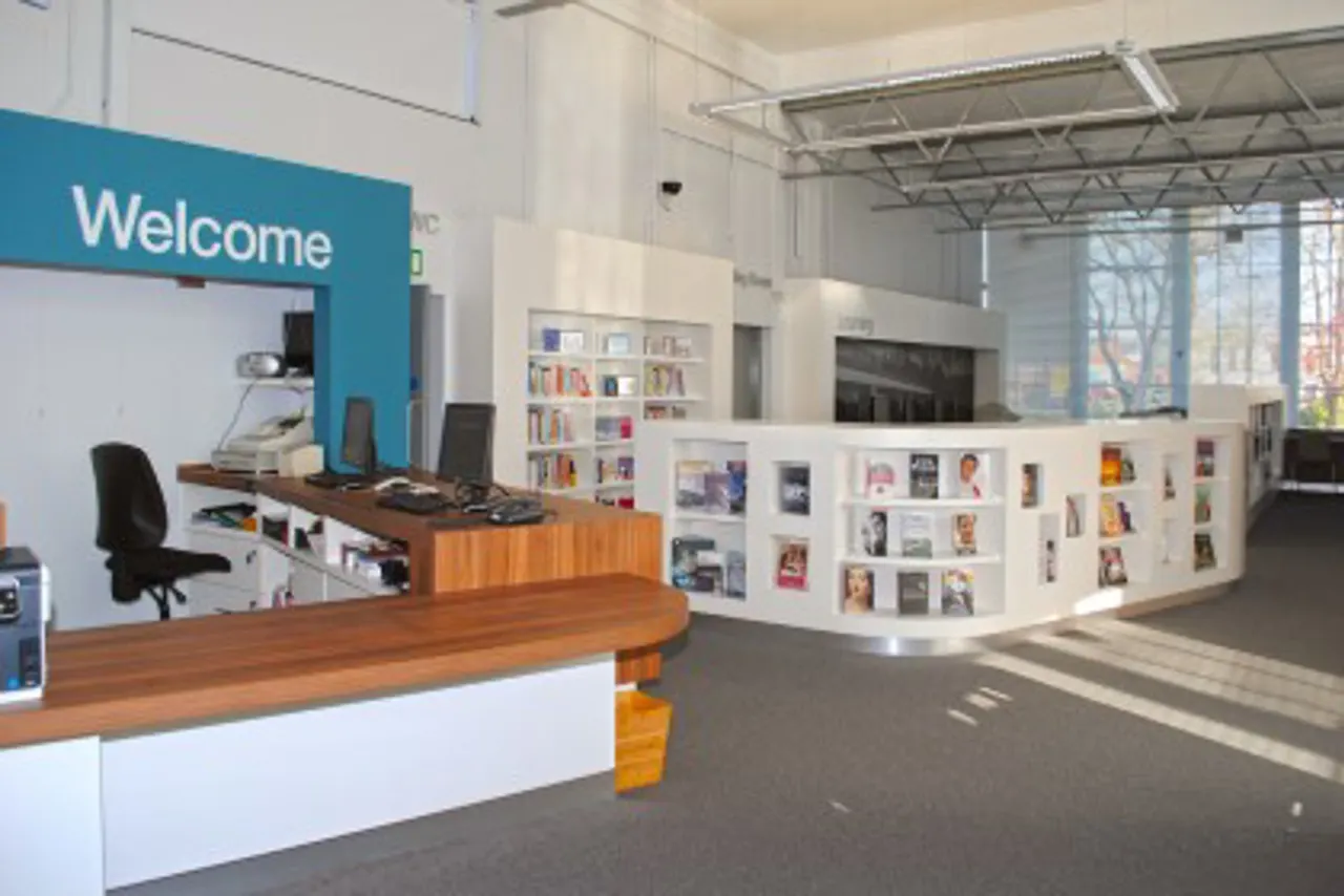 Modern library reception area with welcome desk, bookshelves and large windows.
