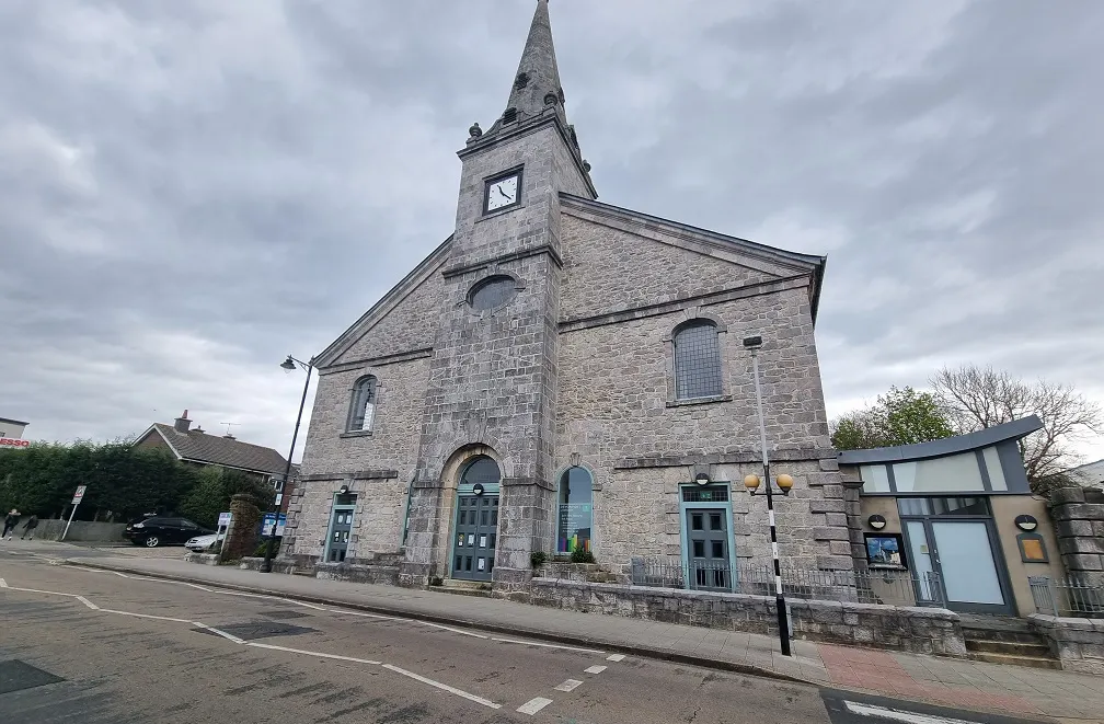 Historic stone chapel building with clock tower converted into a library, viewed from street level.