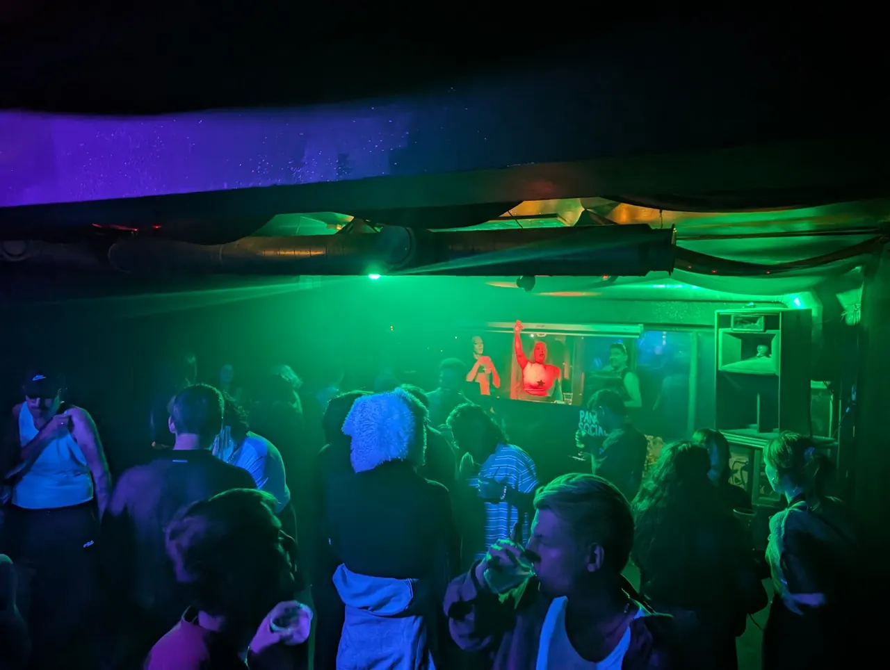 Crowd of visitors watching an illuminated underwater display with glowing fish sculptures and coloured lighting effects.