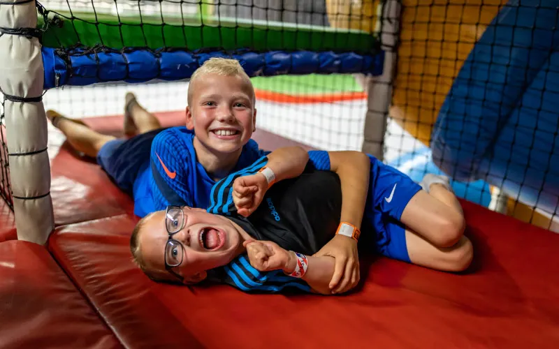 Two children playing and laughing inside a colorful inflatable bouncy castle.