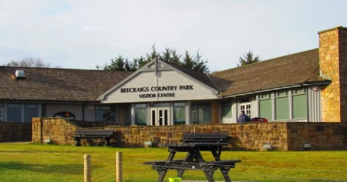 Beecraigs Country Park visitor centre with picnic tables on a grassy lawn.