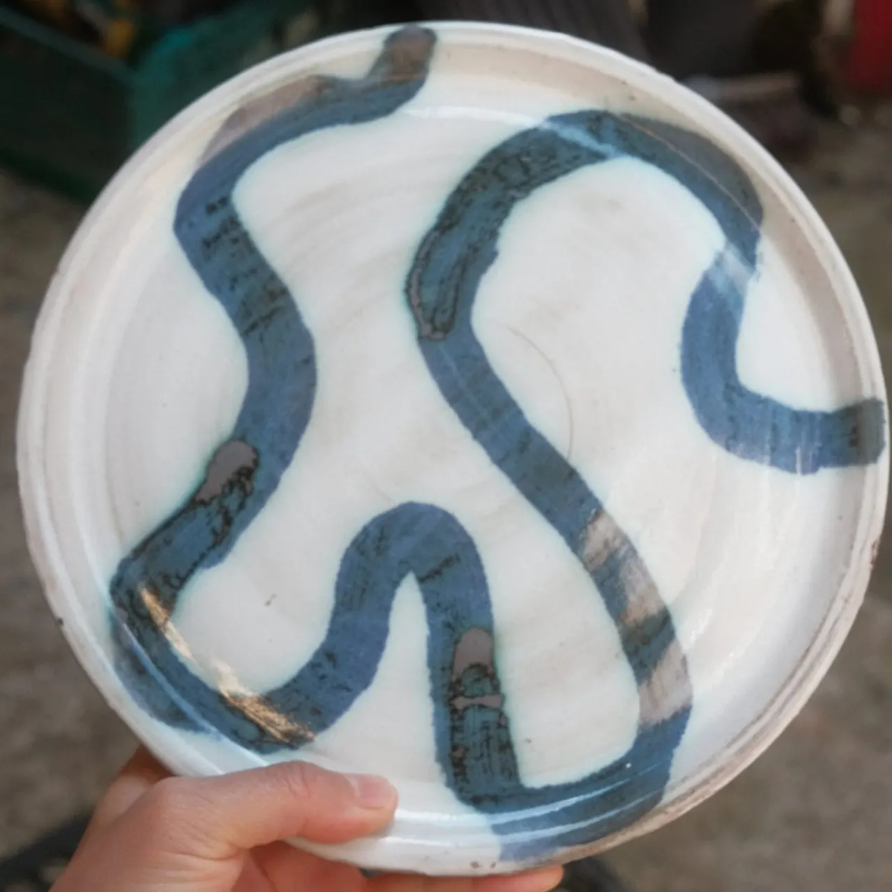 Several blue snakes coiled in a white plastic container held in someone's hand.