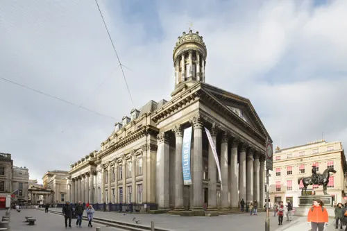 Classical stone building with columned portico and dome, surrounded by public plaza with visitors walking and gathered outside.