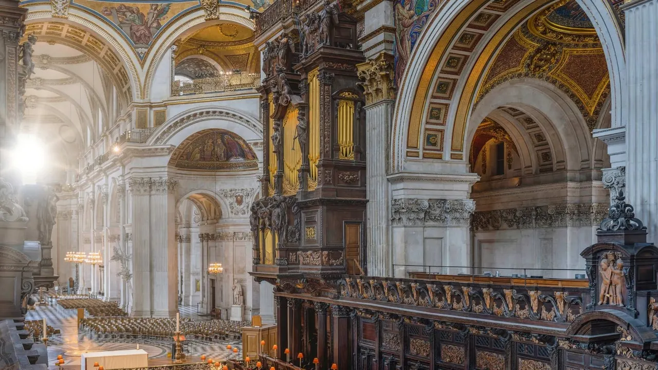 Interior of a grand cathedral with ornate vaulted ceilings, gilded arches, decorative columns and a wooden organ.