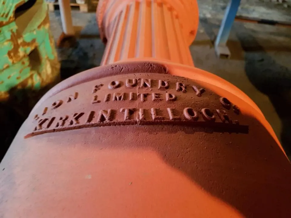 Close-up of embossed text on a large orange cylindrical metal pipe or industrial equipment.