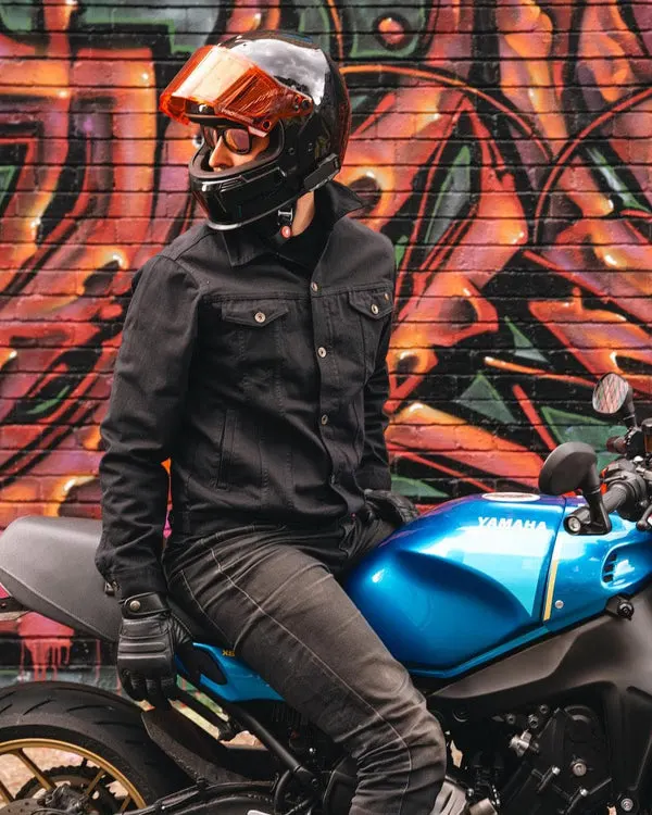 Person in motorcycle helmet and jacket sitting on blue Yamaha bike against colourful graffiti wall.