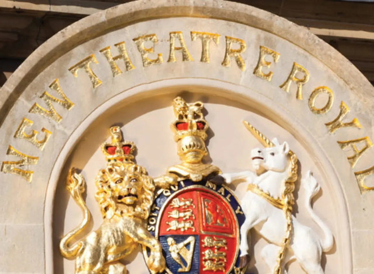 Ornate stone theatre crest with gilt lettering, crowned lion and unicorn supporters, and heraldic shield.