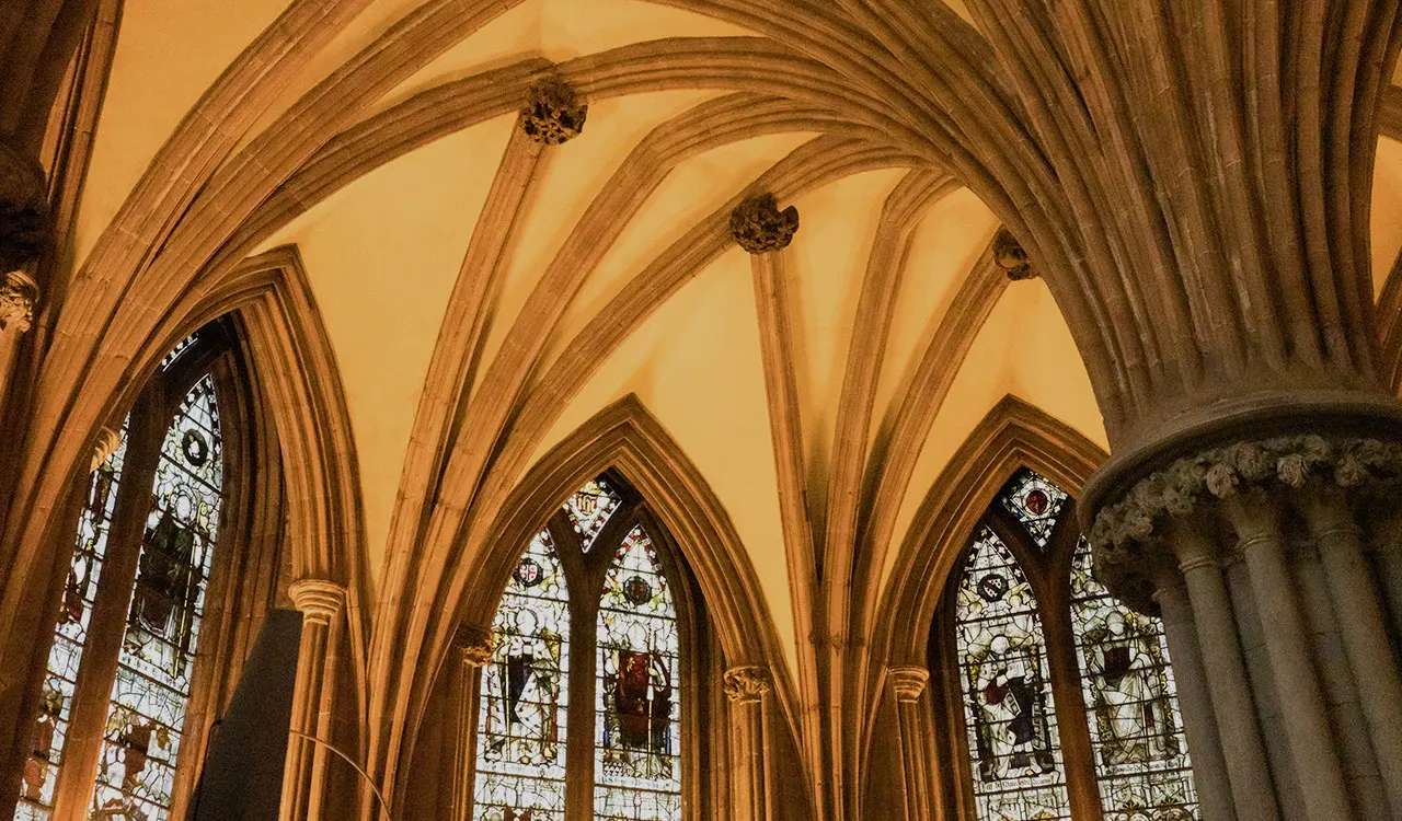 Gothic cathedral interior with soaring stone vaults, ribbed arches and stained glass windows.