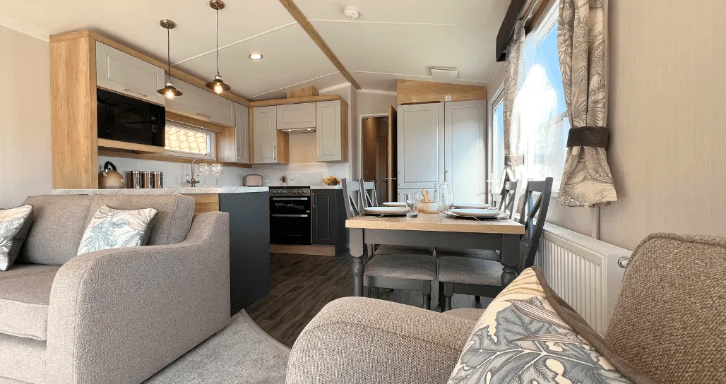 Interior of a modern holiday lodge with open-plan living space, kitchen, dining table and comfortable seating.