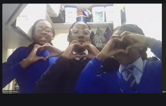 Four young people in blue uniforms making heart shapes with their hands.
