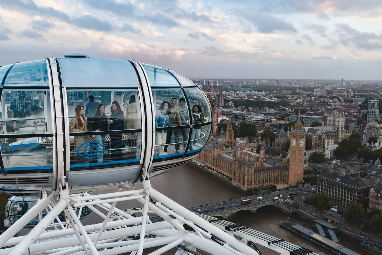 Passengers in a capsule on the London Eye observation wheel with views of London's cityscape, Big Ben and the Thames below.