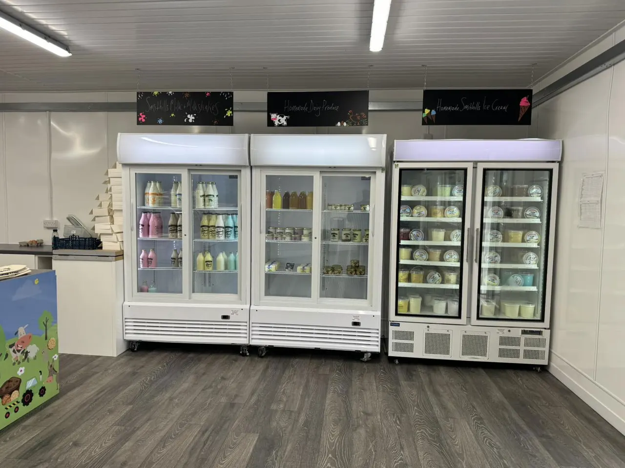 Refrigerated display cases stocked with ice cream containers and dairy products in a shop.