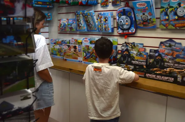 Two children viewing Thomas the Tank Engine toy sets and merchandise displayed on shelves.