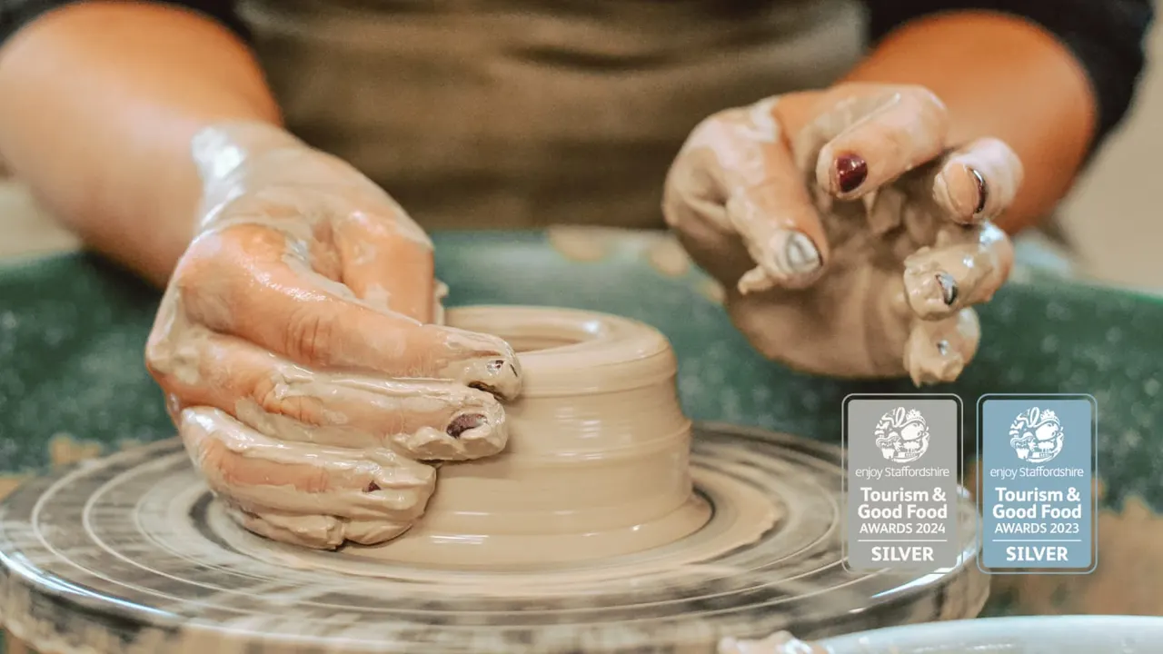 Hands shaping wet clay on a pottery wheel during a ceramics workshop.