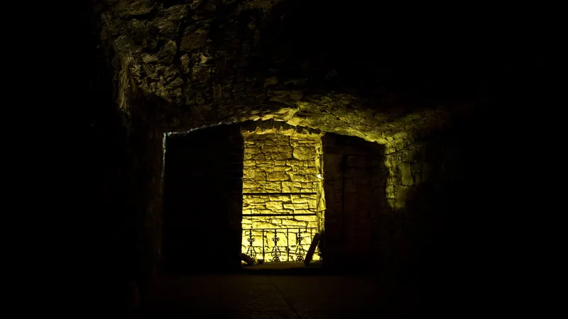 Underground stone chamber illuminated by warm yellow lighting at night.