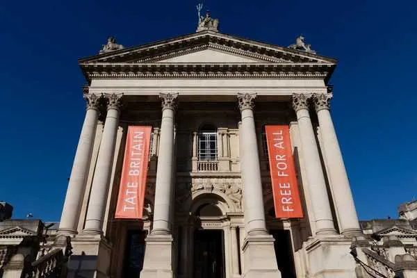 Grand neoclassical museum building with white columns and pediment against clear blue sky.