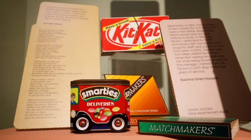 Vintage confectionery packaging including Kit Kat and Smarties boxes displayed with printed historical text documents.