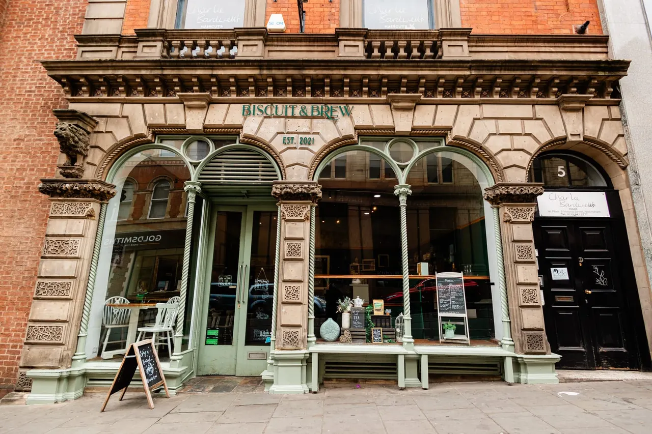 Victorian shopfront for Biscuit & Brew tea house with ornate columns, green-framed windows and red brick facade.