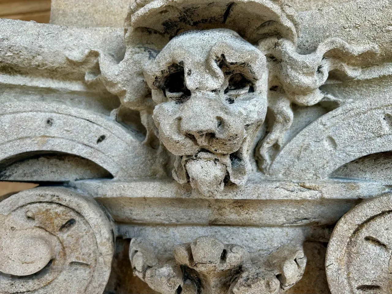 Stone architectural ornament featuring a carved lion head with decorative scrollwork and mouldings.