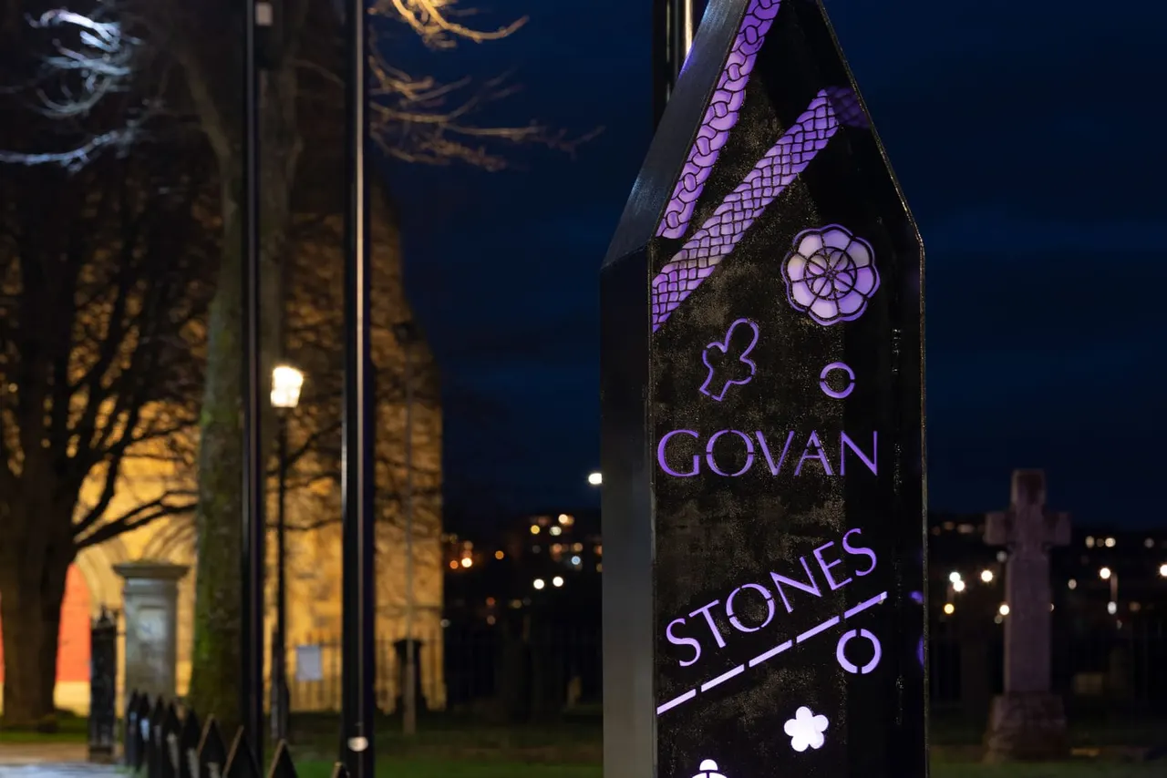 Illuminated purple neon sign for Govan Stones Museum at night, with historic buildings and city lights visible in background.