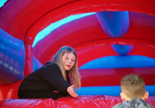 Young child playing inside a red and blue inflatable bounce house.