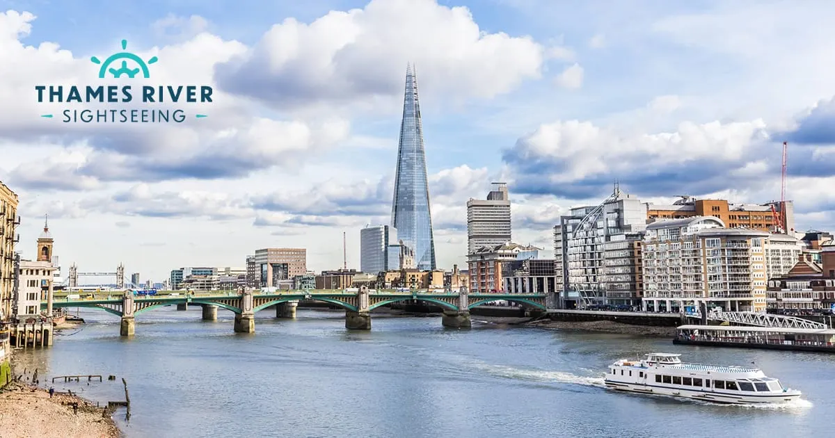 A sightseeing boat on the Thames with Southwark Bridge, The Shard and London's skyline visible across the river.