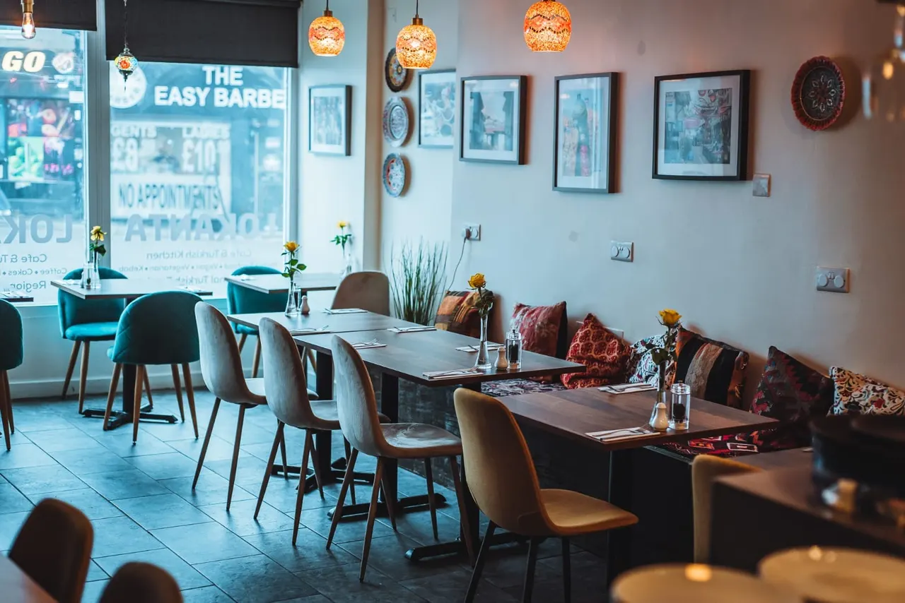 Interior of a modern Turkish restaurant with dining tables, cushioned seating, decorative plates and pendant lighting.