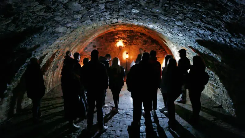 Group of visitors gathered inside an illuminated stone tunnel or underground chamber.